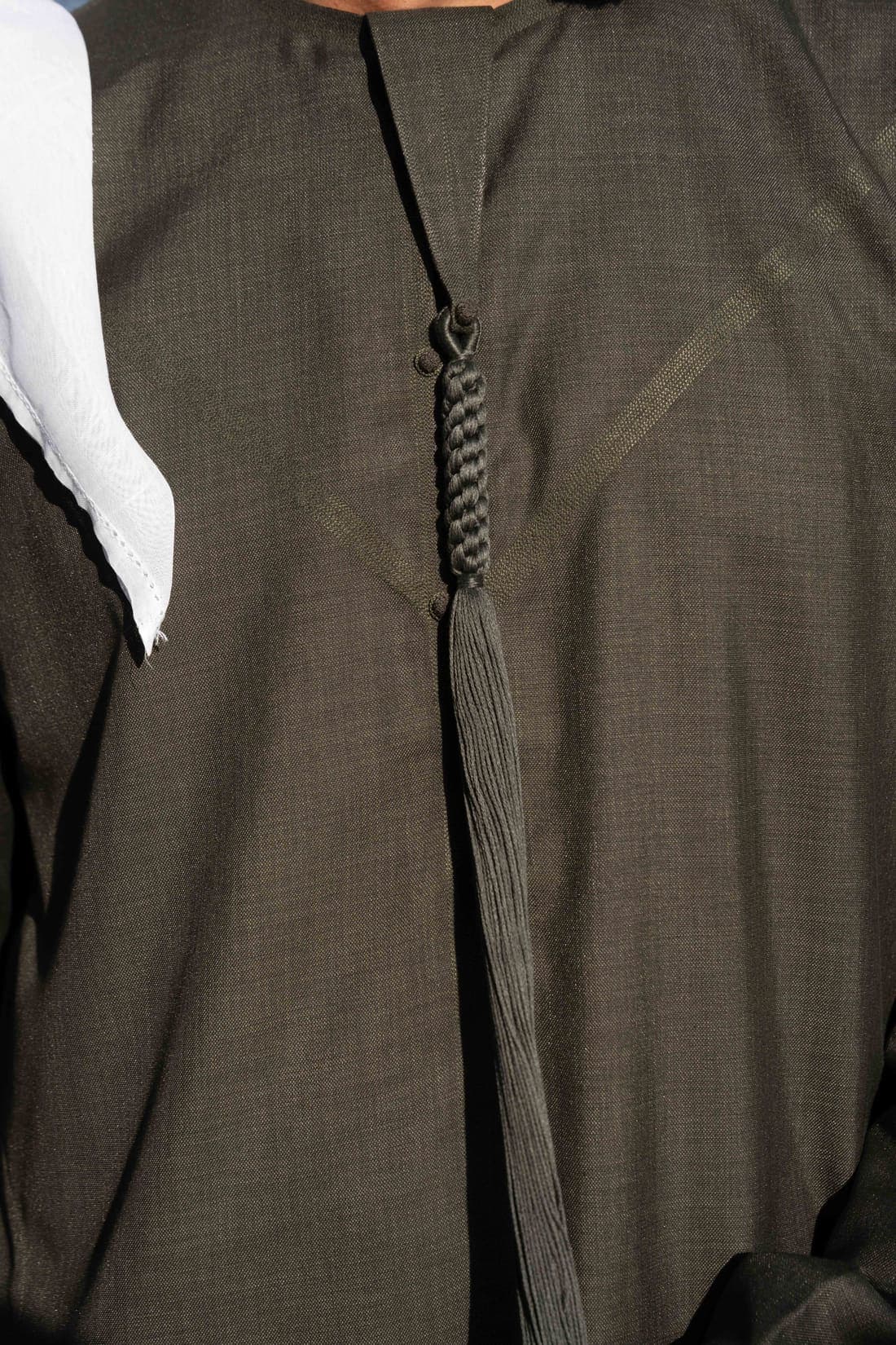 Close view of an olive kandura, showing the weave of the Japanese fabric and the tarboosh.